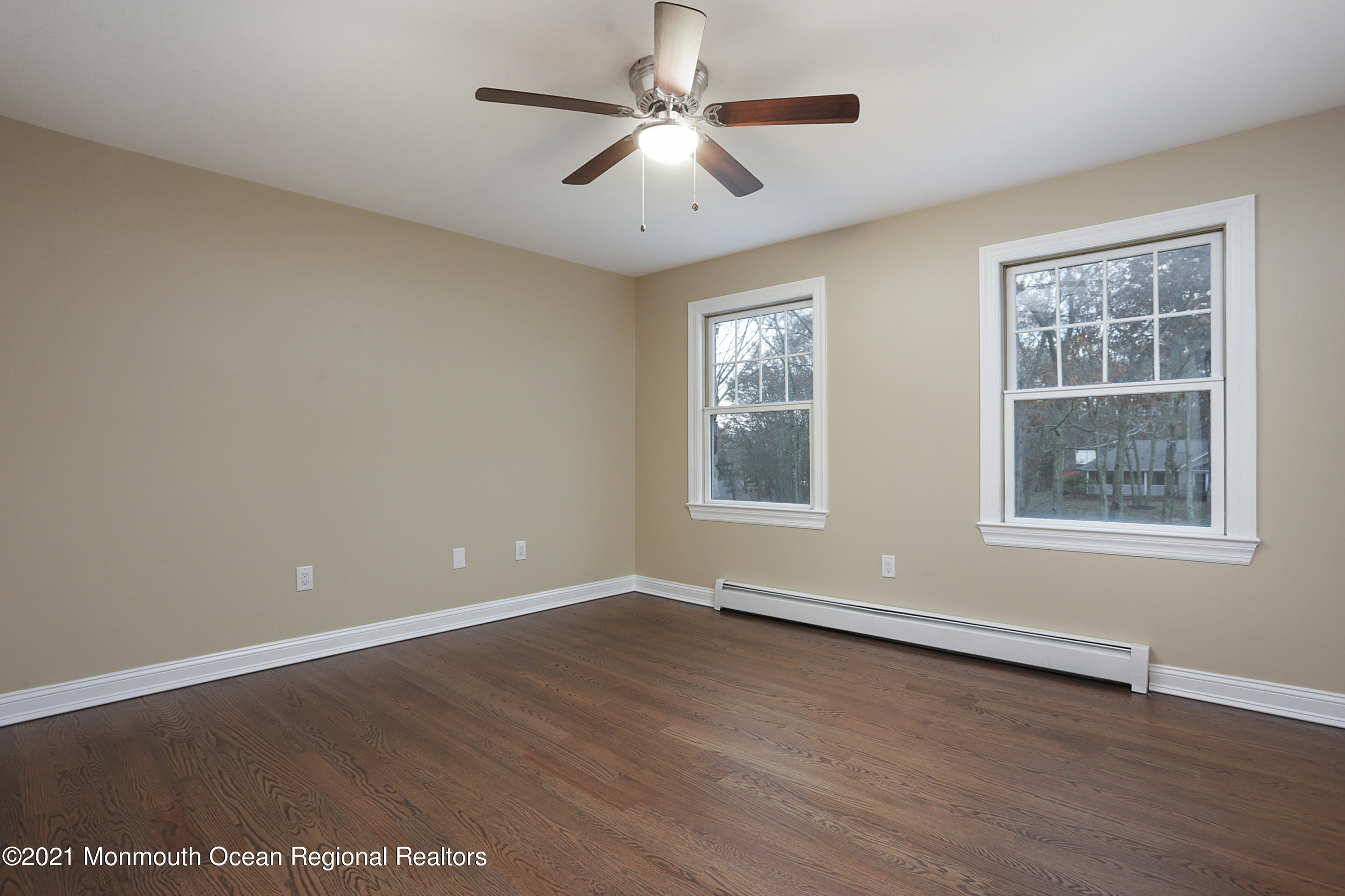 2104 Shadowbrook Drive Wall, NJ 07719 - Photo 36 of 84 an empty room with wooden floor chandelier fan and windows