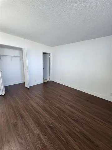 a view of an empty room with wooden floor and closet