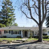 a front view of a house with a garden and trees