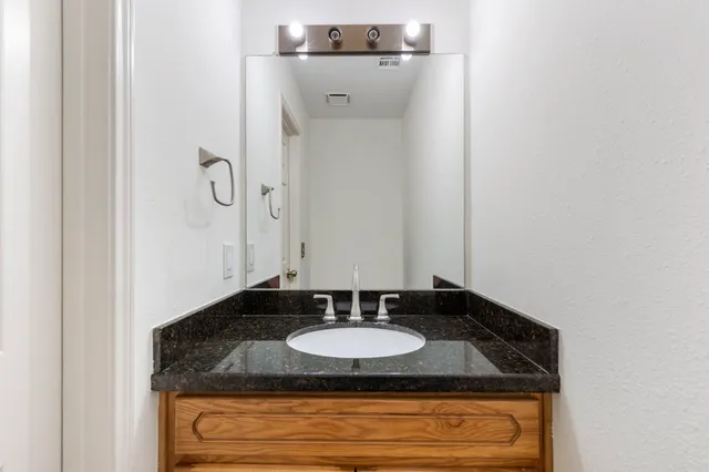 a bathroom with a granite countertop sink and a mirror