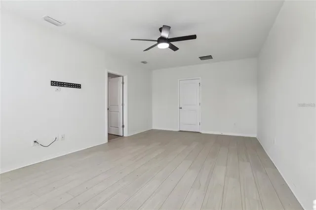 an empty room with a ceiling fan and wooden floor