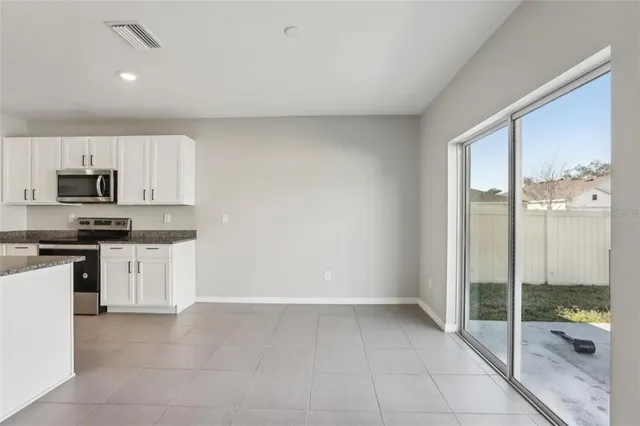 a kitchen with granite countertop a refrigerator and white cabinets