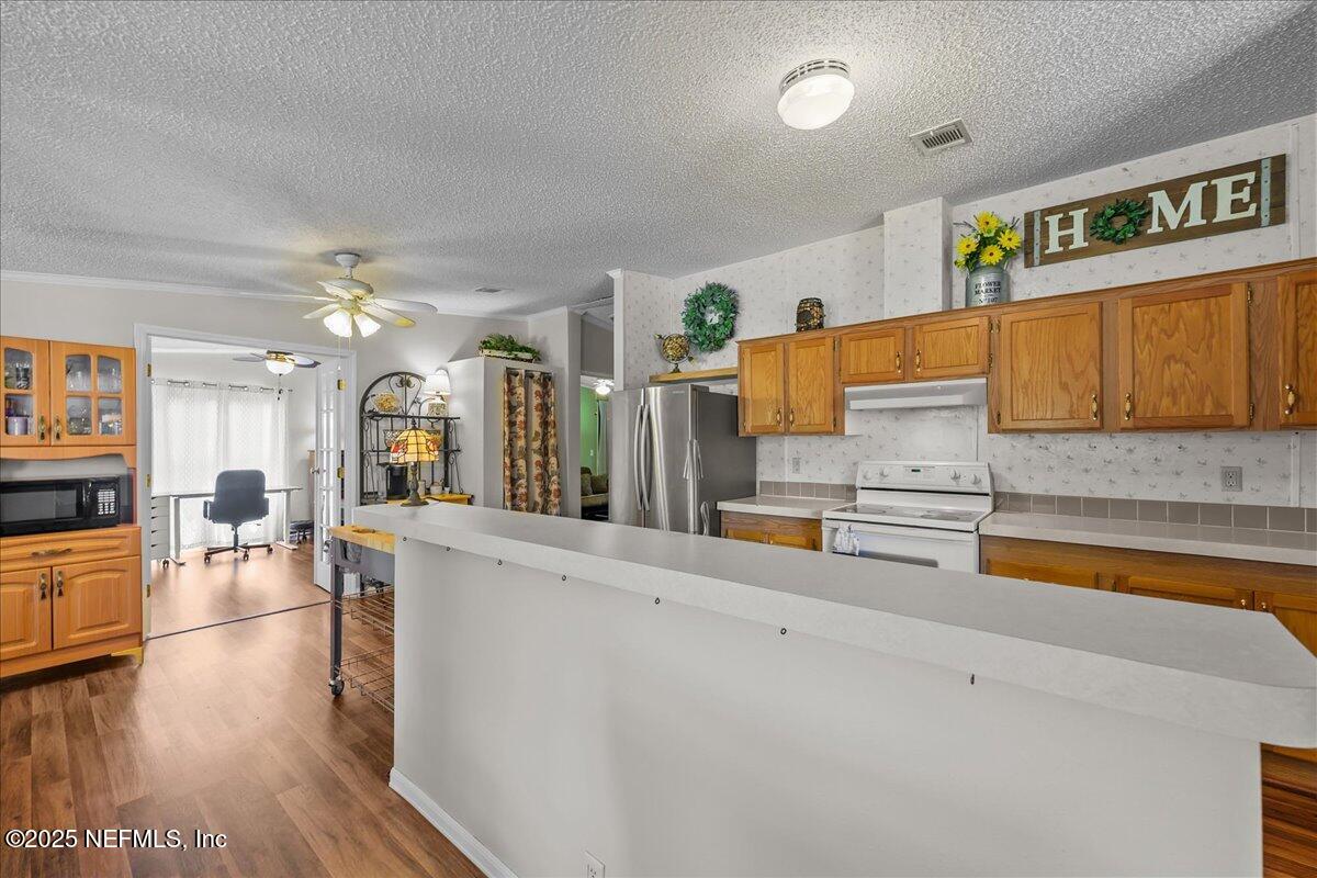 54451 Marsh Road Callahan, FL 32011 - Photo 7 of 26 a kitchen with stainless steel appliances wooden floor and a refrigerator