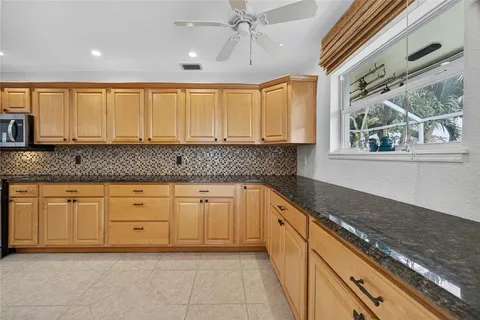 a kitchen with granite countertop white cabinets white appliances a sink and a large window