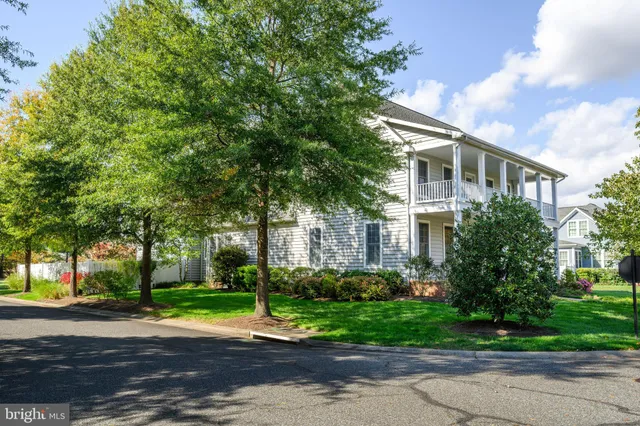 a small white house with a yard and a large tree
