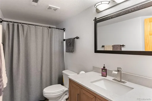 a bathroom with a sink a toilet a mirror and shower curtain