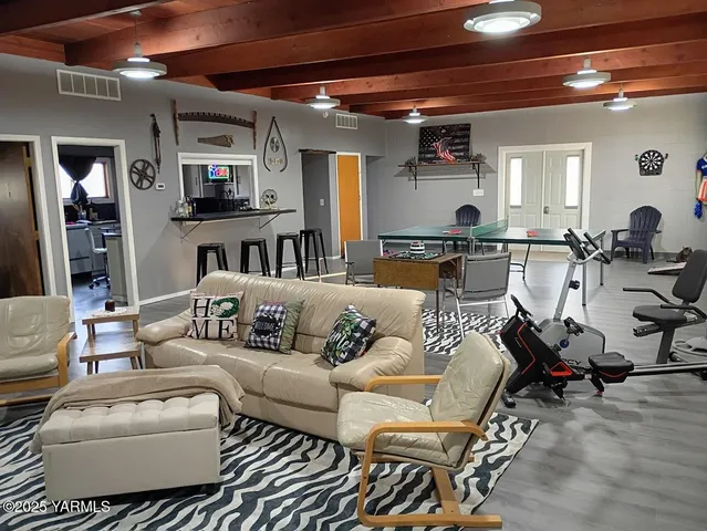 a living room with furniture and a glass table with wooden floor