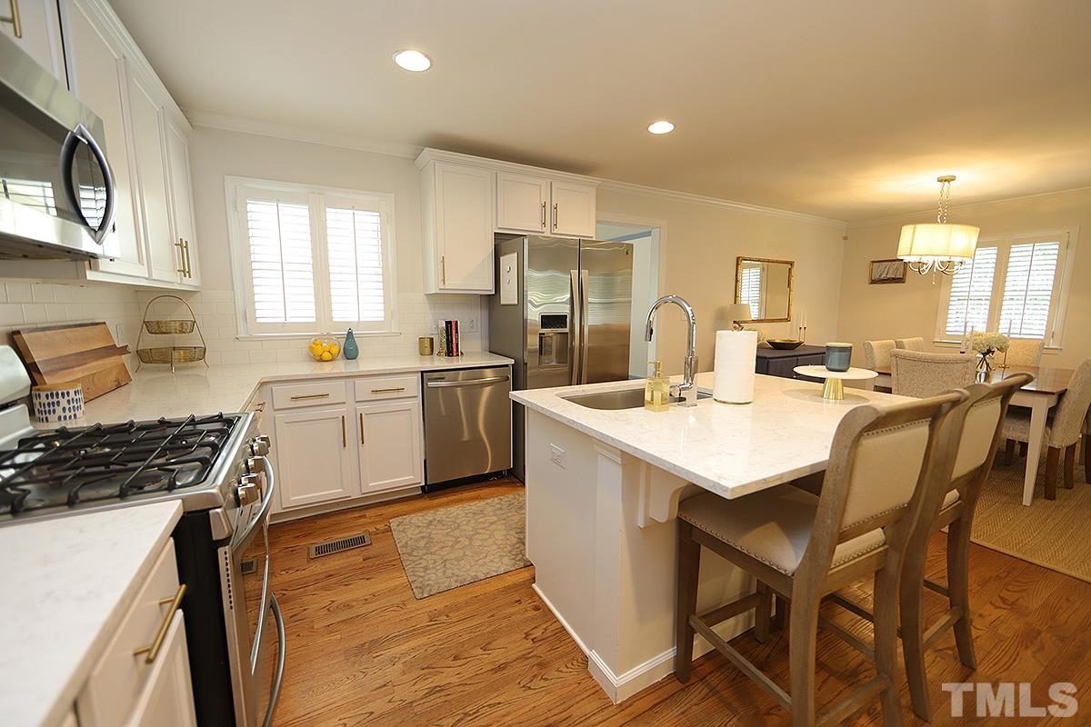 3404 Blue Ridge Road Raleigh, NC 27612 - Photo 13 of 36 a kitchen with a sink a stove a refrigerator cabinets and dining table