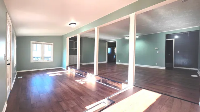 a view of an empty room with wooden floor and a window