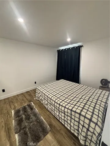 a bedroom with a bed and a lamp with wooden floor