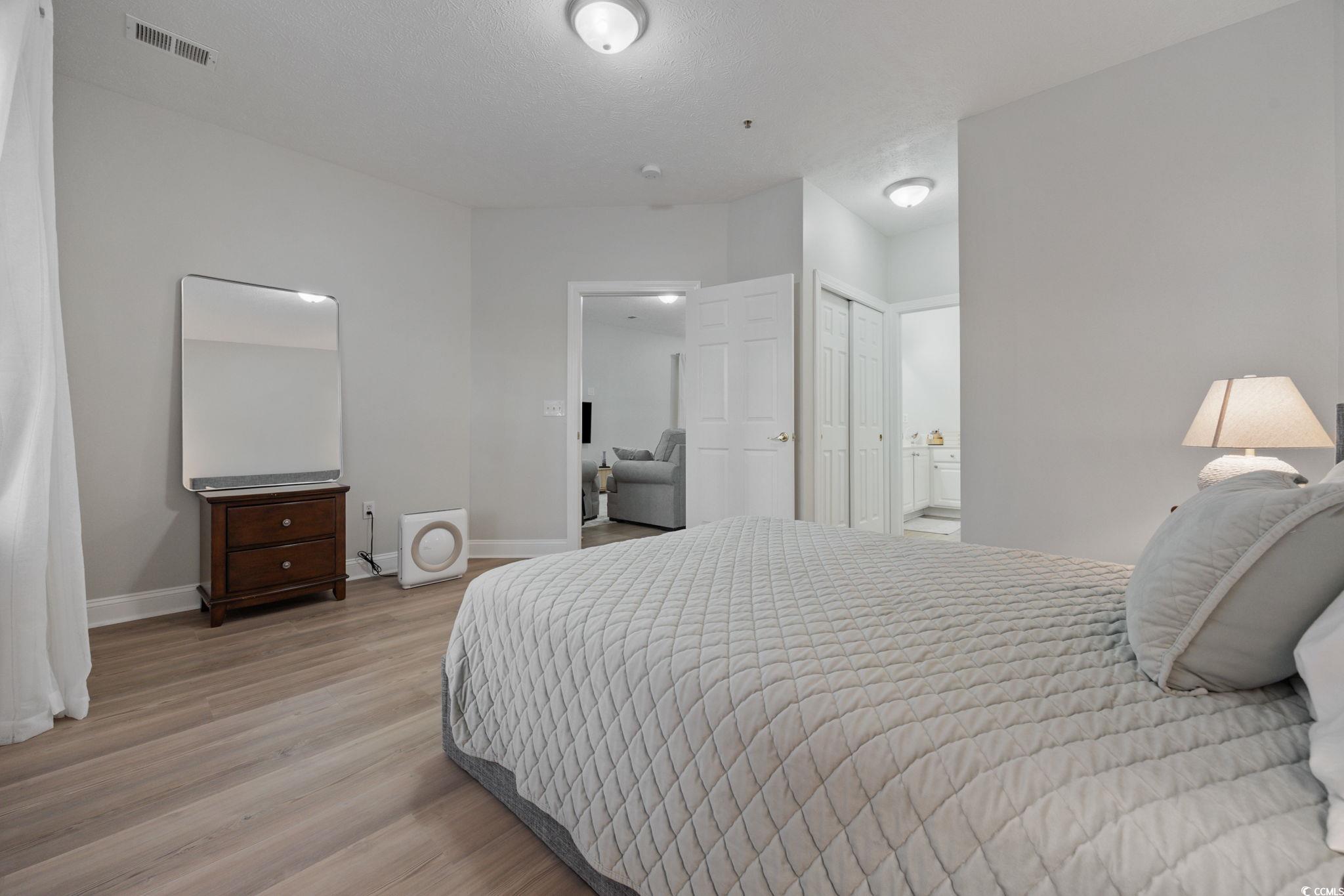 111 Fountain Pointe Lane, Unit 104 Myrtle Beach, SC 29579 - Photo 15 of 30 Bedroom with light wood-style flooring, a closet, and ensuite bathroom