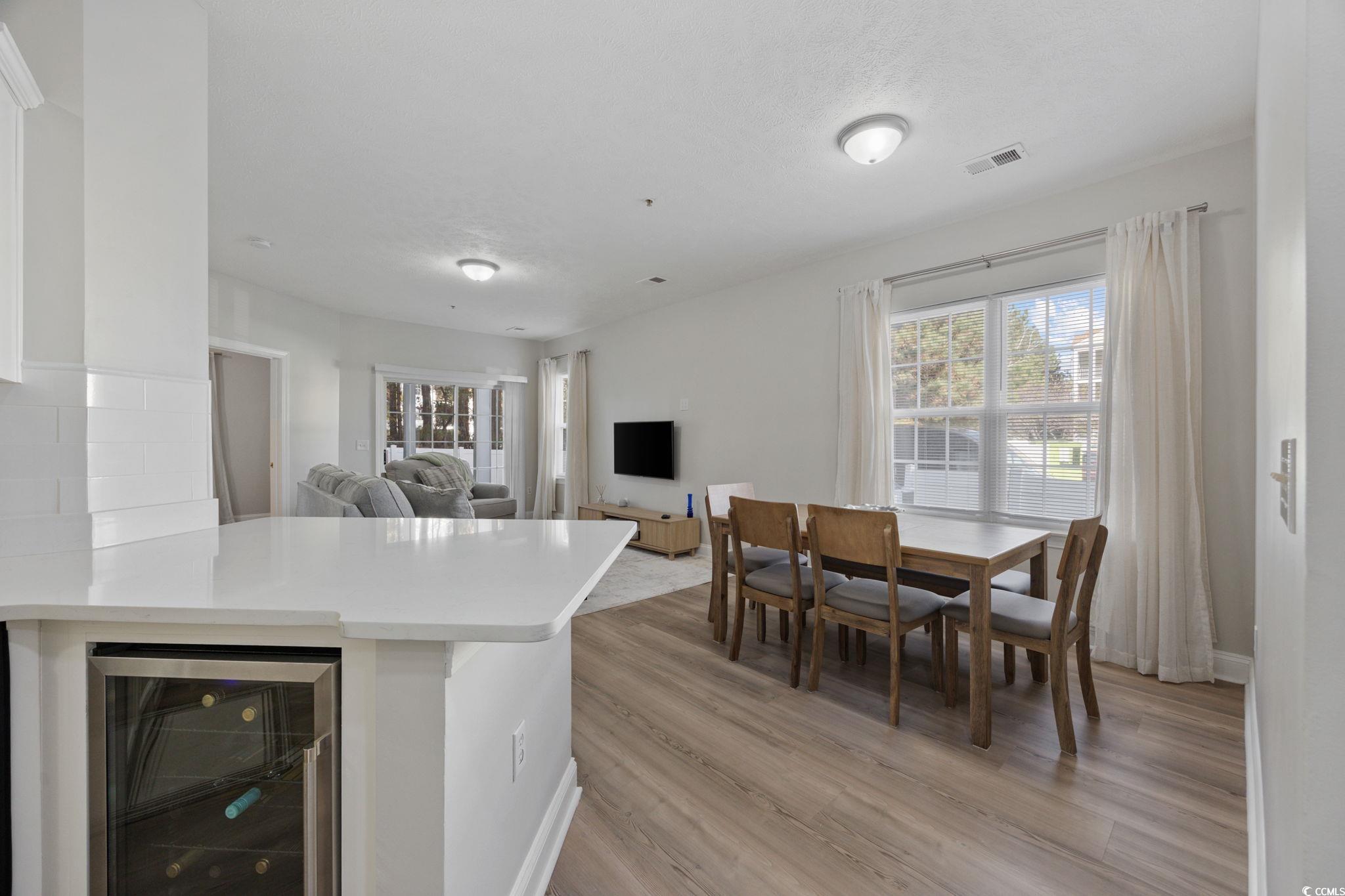 111 Fountain Pointe Lane, Unit 104 Myrtle Beach, SC 29579 - Photo 30 of 30 Kitchen featuring beverage cooler, a peninsula, light wood finished floors, open floor plan, and light stone countertops