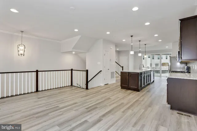 a living room with stainless steel appliances kitchen island hardwood floor and a sink