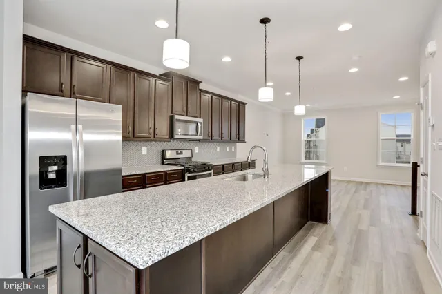 a kitchen with kitchen island a counter top space a sink cabinets and stainless steel appliances