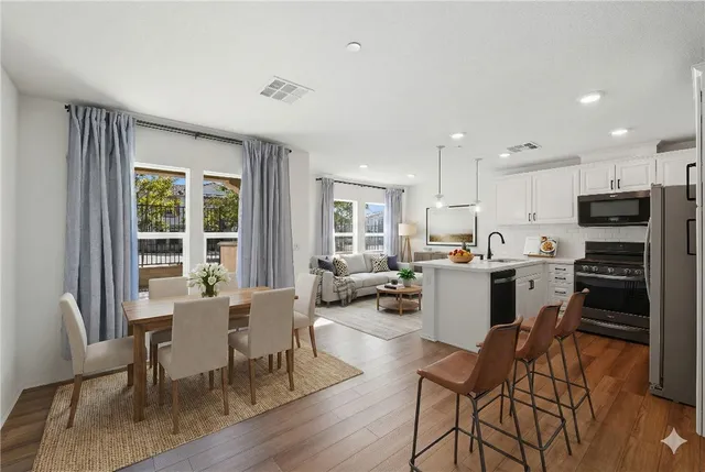 a living room with stainless steel appliances kitchen island granite countertop furniture and a wooden floor