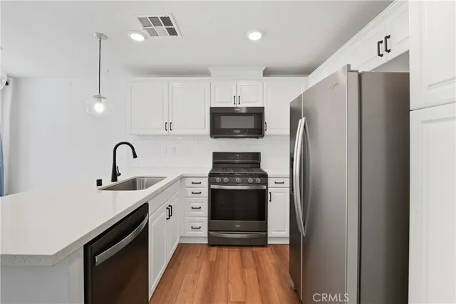 a kitchen with stainless steel appliances a refrigerator sink and white cabinets