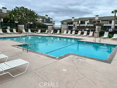 a view of a swimming pool with a lawn chairs and potted plants