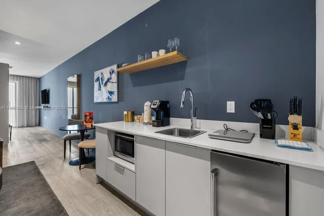 a kitchen with a sink dishwasher and white cabinets with wooden floor