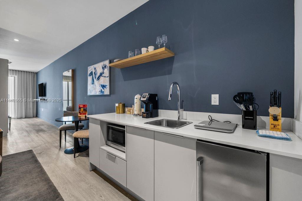 239 Southwest 9th Street, Unit 602 Miami, FL 33130 - Photo 6 of 18 a kitchen with a sink dishwasher and white cabinets with wooden floor