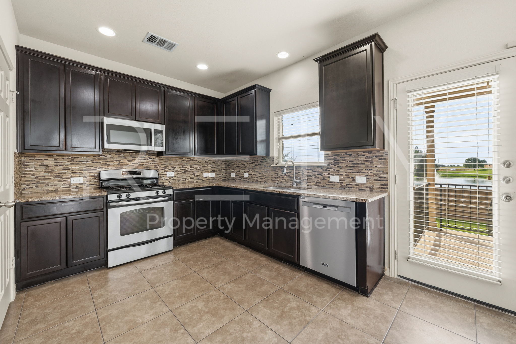 1405 Sunny Meadows Loop Georgetown, TX 78626 - Photo 10 of 40 A well-appointed kitchen showcasing elegant dark cabinetry and a convenient outdoor access point.