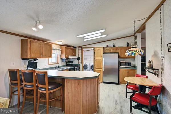 a kitchen with stainless steel appliances kitchen island granite countertop a refrigerator a stove and a dining table with wooden floor
