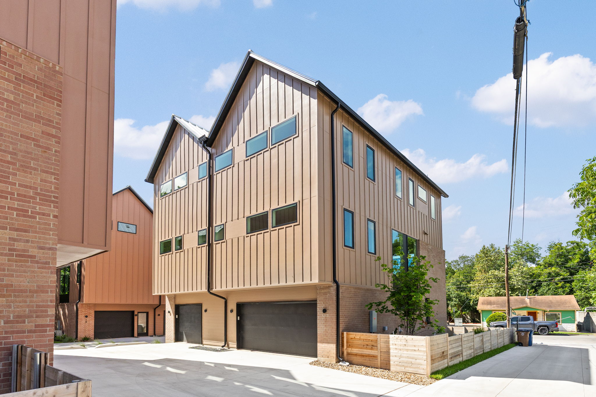 732 Springdale Road, Unit A Austin, TX 78702 - Photo 16 of 18 Modern townhomes showcasing striking vertical siding and integrated garages, creating a dynamic urban aesthetic.
