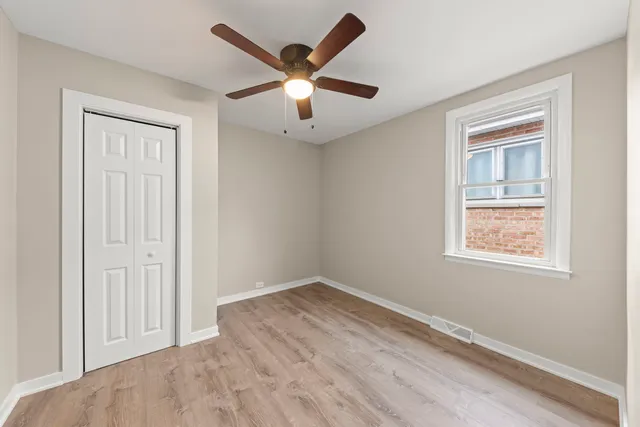an empty room with wooden floor ceiling fan and windows