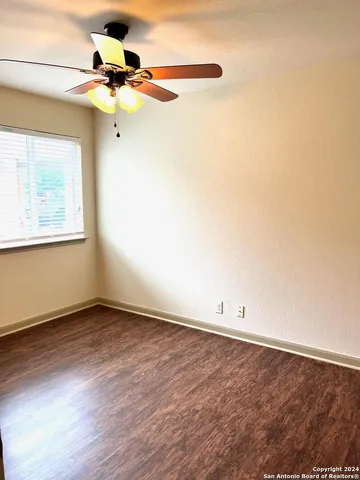 an empty room with a window and a ceiling fan