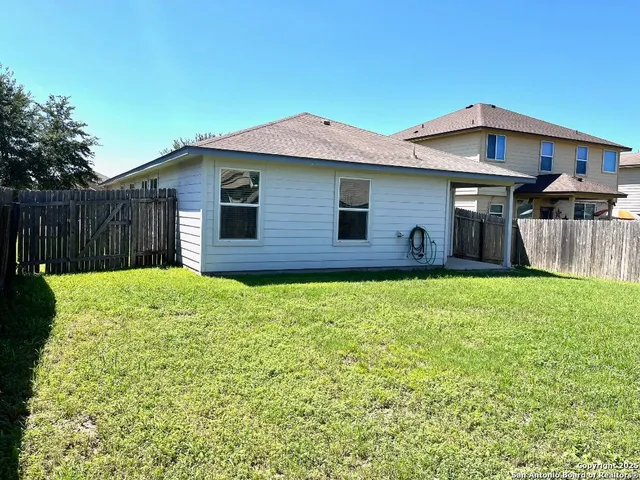 a brick house with a small yard and wooden fence