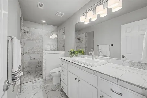 a bathroom with a double vanity sink toilet and shower