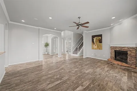 a view of a livingroom with a fireplace a ceiling fan and wooden floor
