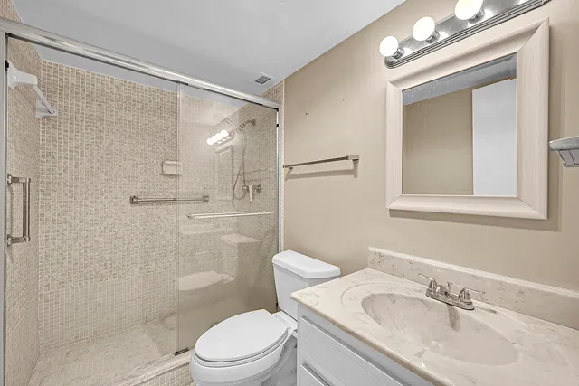 a bathroom with a sink vanity granite toilet and shower