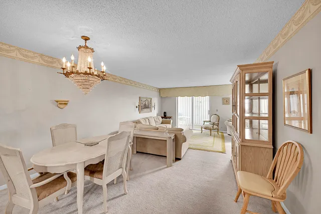a view of a dining room with furniture a chandelier and a large window