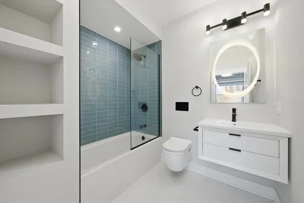 a bathroom with a bathtub shower sink mirror and toilet