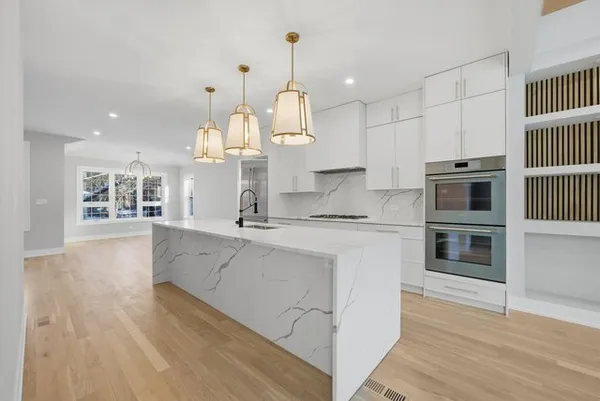 a kitchen with stainless steel appliances granite countertop a stove oven and white cabinets with wooden floor