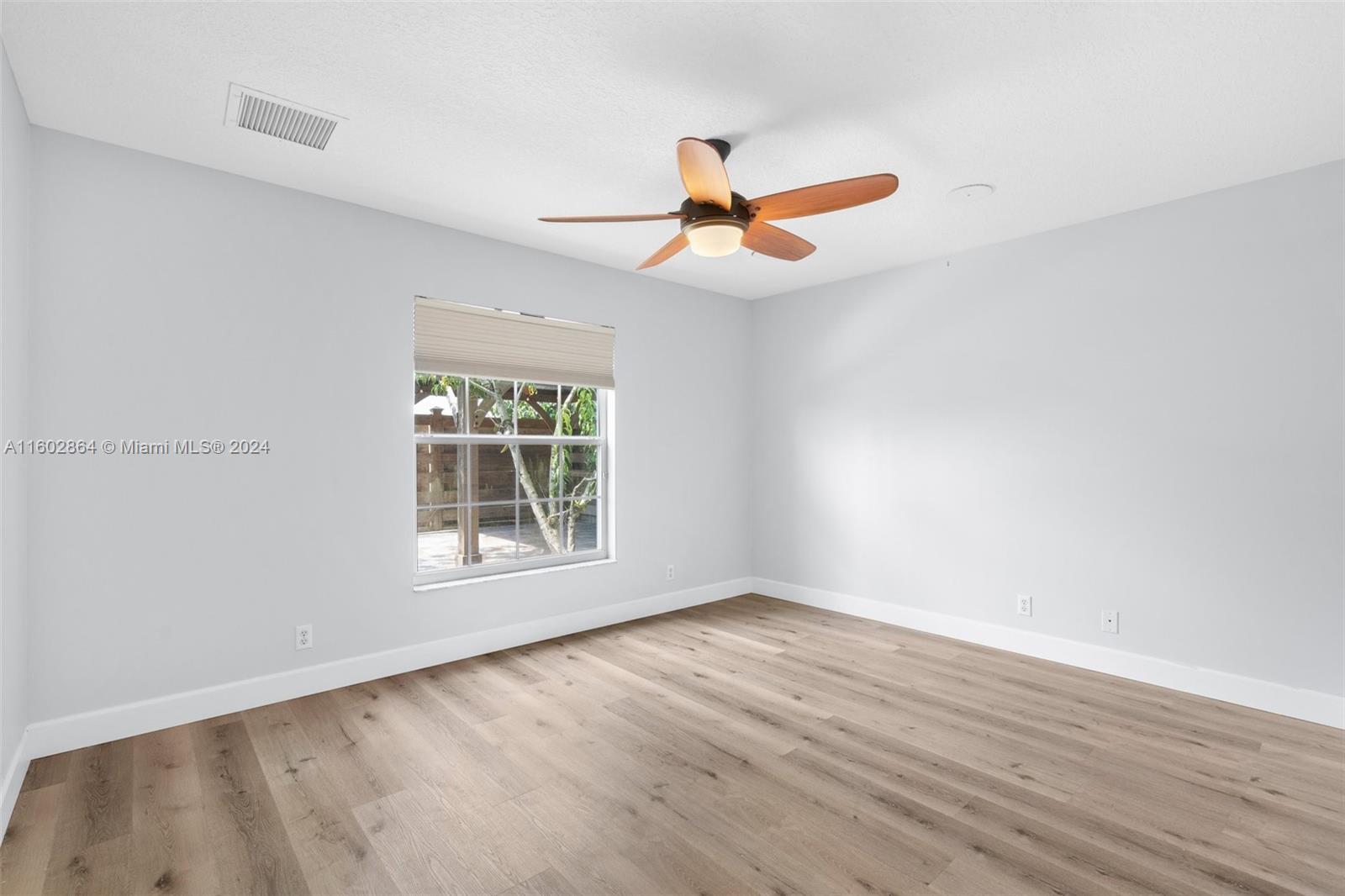 6054 Foster Street Jupiter, FL 33458 - Photo 30 of 50 an empty room with wooden floor ceiling fan and window