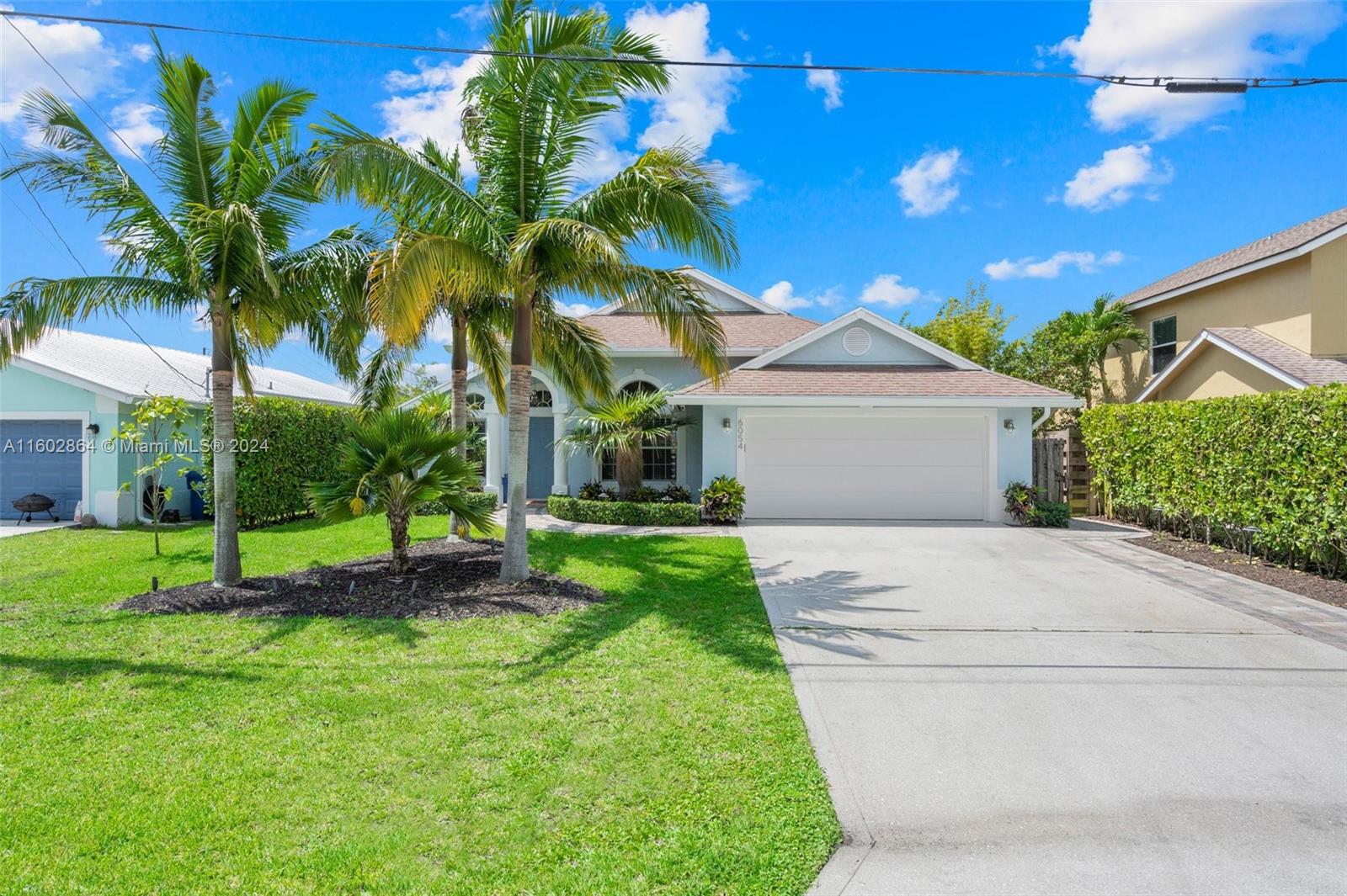6054 Foster Street Jupiter, FL 33458 - Photo 7 of 50 a front view of a house with a yard and garage