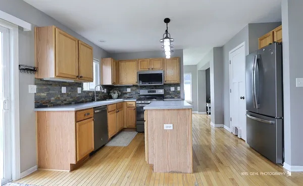a kitchen with stainless steel appliances granite countertop a refrigerator a stove top oven a sink dishwasher and wooden floor