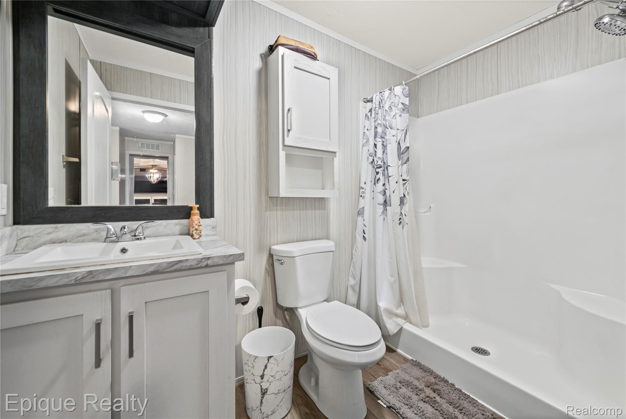 83 Elm Highland, MI 48357 - Photo 20 of 27 Bathroom with vanity, a stall shower, wallpapered walls, crown molding, and wood finished floors