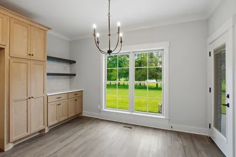 an empty room with wooden floor cabinet and windows