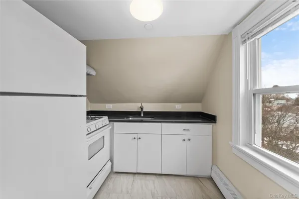 a kitchen with granite countertop white cabinets and white appliances