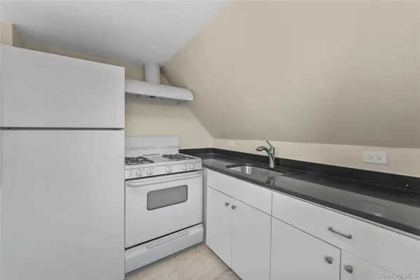 a kitchen with granite countertop white cabinets and white appliances