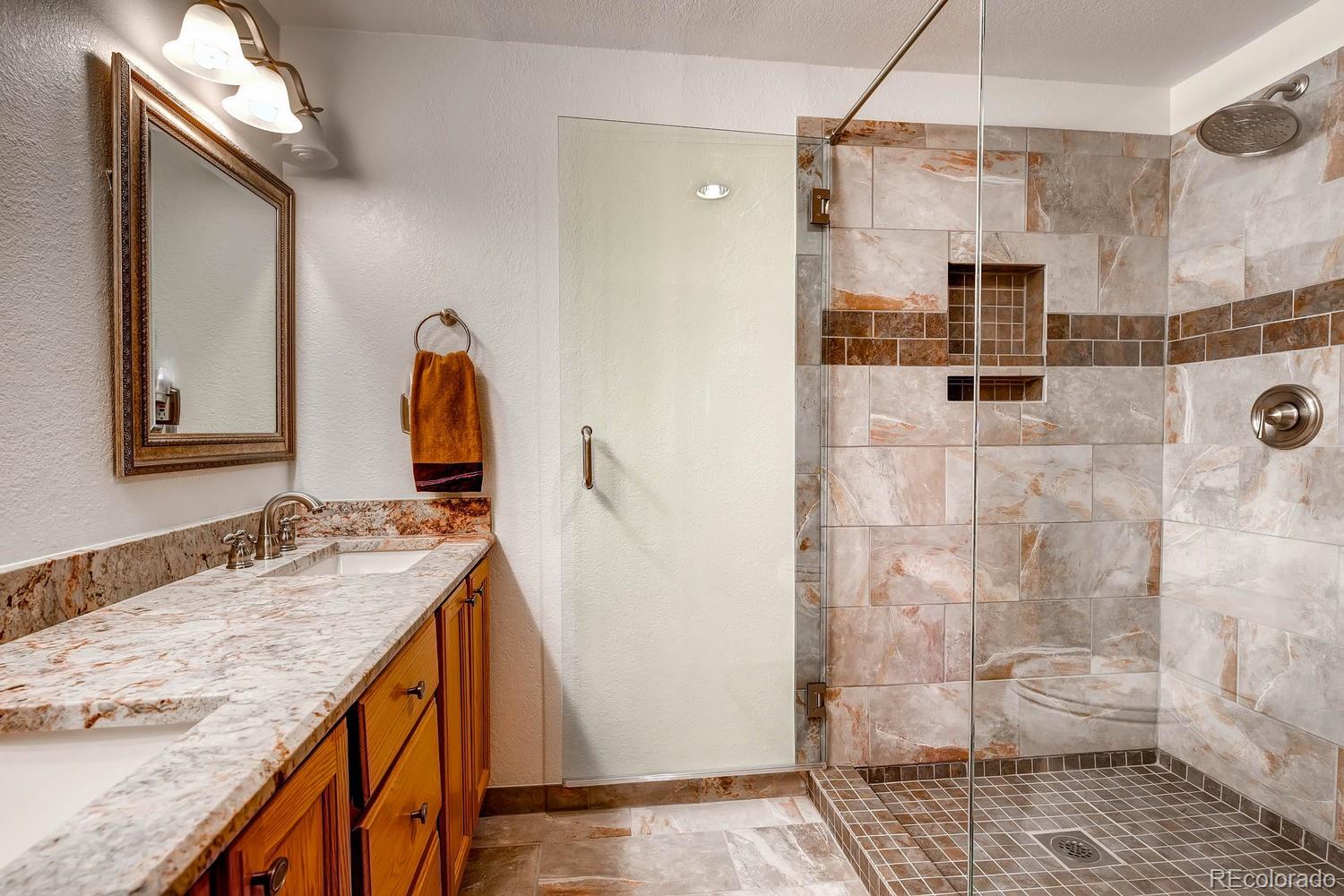 9470 Kemper Drive Lone Tree, CO 80124 - Photo 30 of 35 a bathroom with a granite countertop sink a mirror and shower