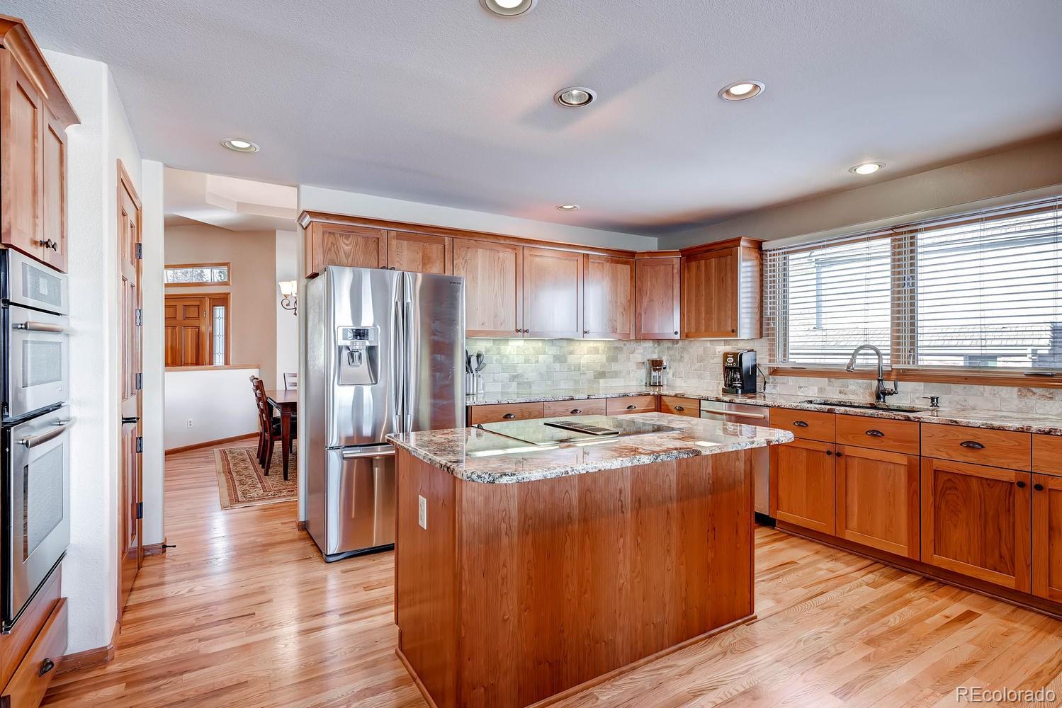 9470 Kemper Drive Lone Tree, CO 80124 - Photo 7 of 35 a kitchen with stainless steel appliances granite countertop a refrigerator a sink dishwasher a stove and white countertops with wooden floor