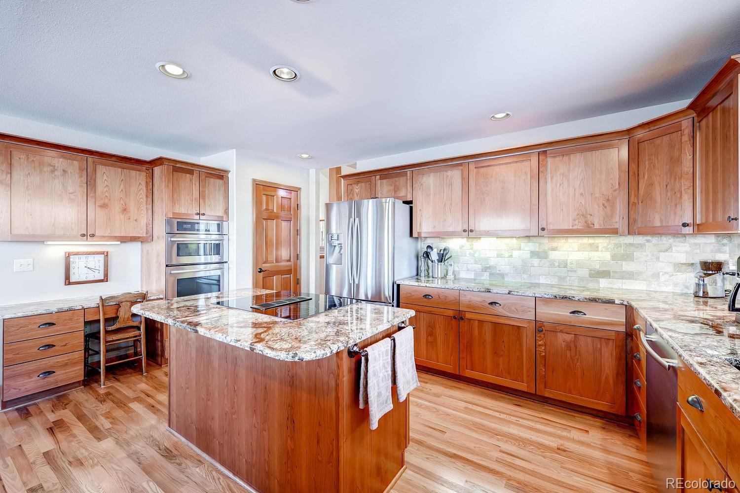 9470 Kemper Drive Lone Tree, CO 80124 - Photo 8 of 35 a kitchen with stainless steel appliances granite countertop wooden cabinets a sink and dishwasher a stove top oven with wooden floor