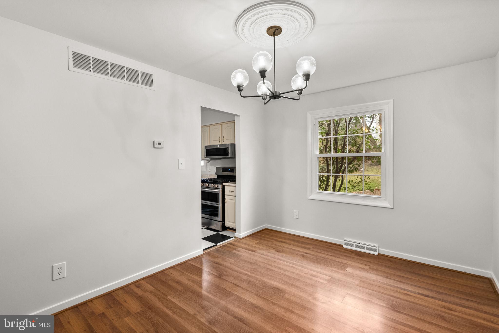 6170 Commodore Court Columbia, MD 21045 - Photo 6 of 49 an empty room with wooden floor chandelier and windows