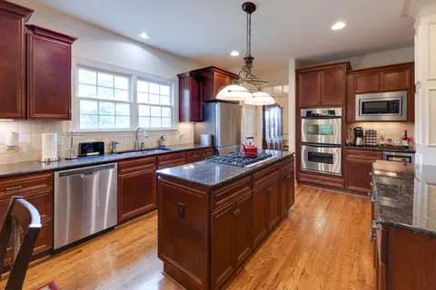 a kitchen with stainless steel appliances granite countertop a stove and a wooden floors