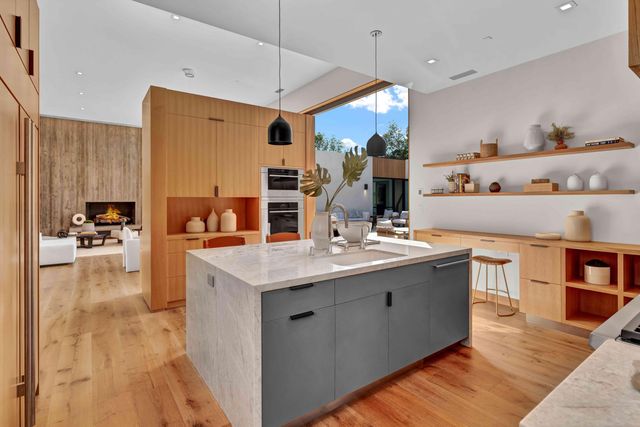 a kitchen with stainless steel appliances granite countertop a sink a stove a refrigerator and island with wooden floor