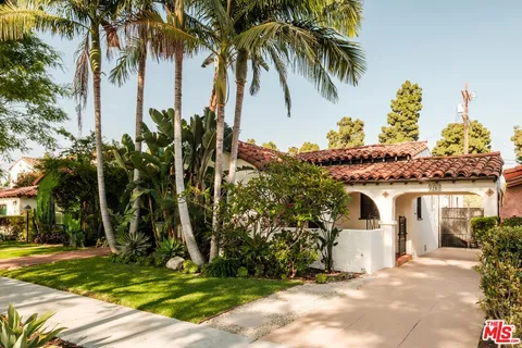a view of a white house with a yard and palm trees
