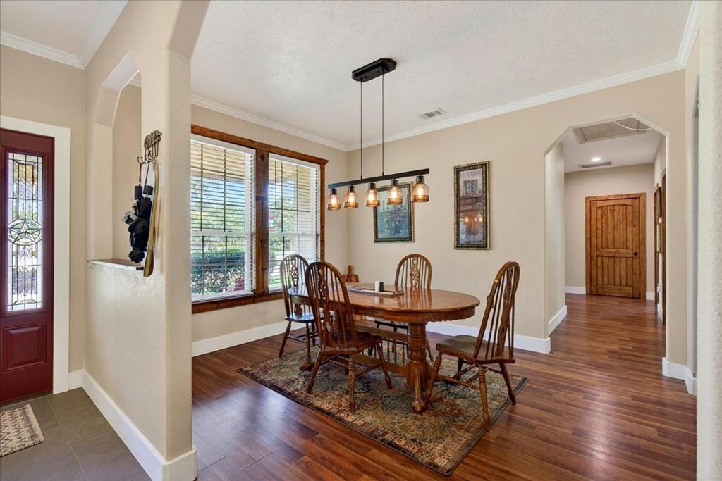11591 Farm To Market 59 Athens, TX 75751 - Photo 9 of 40 Dining area featuring wood-finish flooring, a linear chandelier, and expansive windows with wooden trim, open to living-office-kitchen.